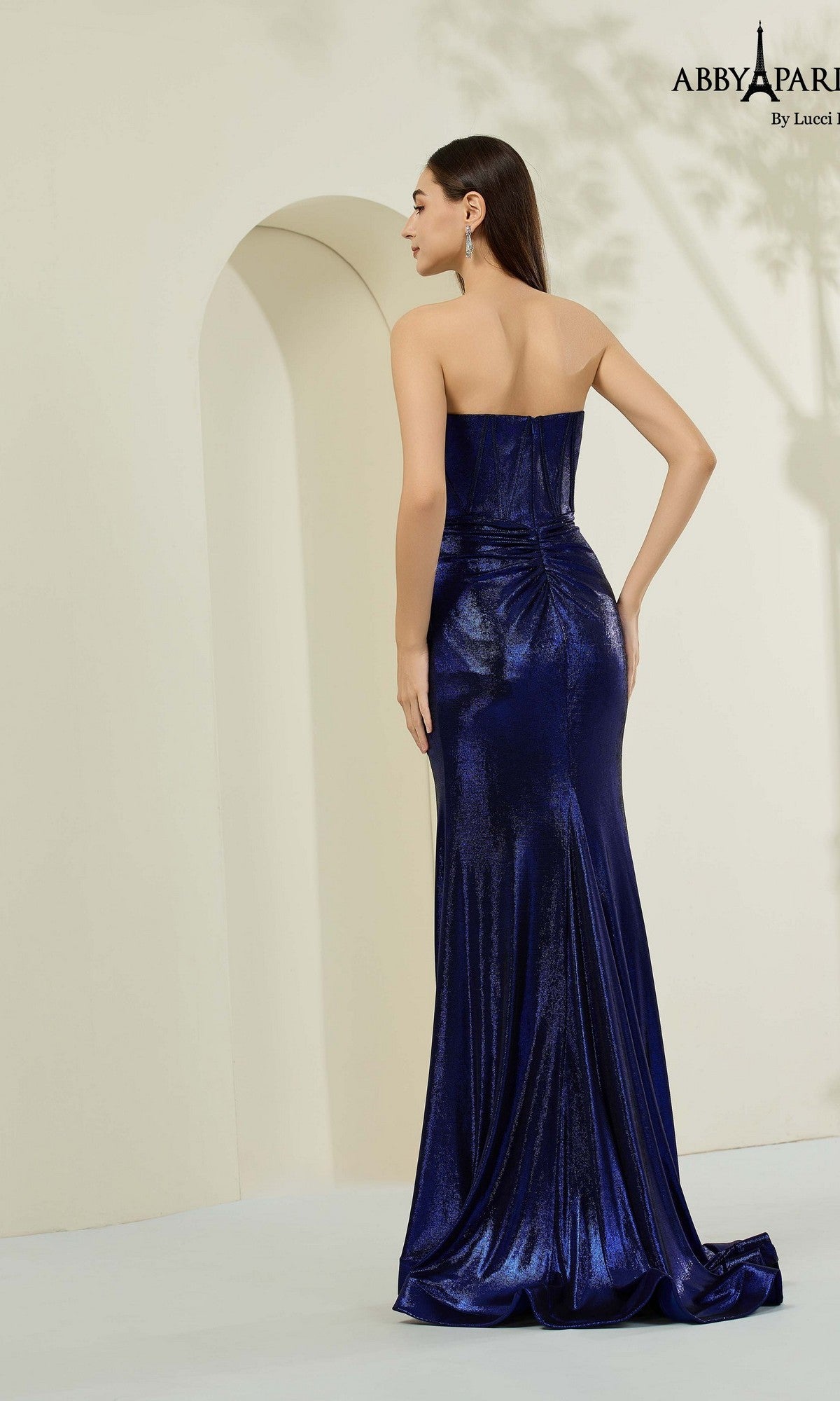 A woman in the Abby Paris 90368 long prom dress, featuring a blue strapless metallic satin design with a corset bodice.